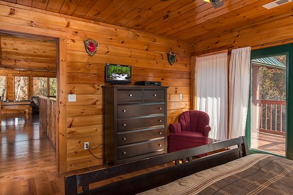 Dresser, TV, and deck access off the king bedroom at Rocky Top Lodge, a 3 bedroom cabin rental located in Pigeon Forge