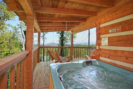 A hot tub and porch swing on a covered deck at Do Not Disturb, a 1-bedroom cabin rental located in Pigeon Forge