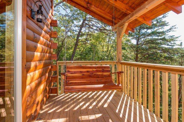 Swing on a covered deck at Canyon Camp Falls, a 2 bedroom cabin rental located in Pigeon Forge