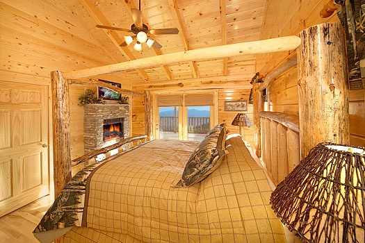 King sized log canopy bed and fireplace in bedroom at Elk Ridge Lodge, a 4-bedroom cabin rental located in Gatlinburg