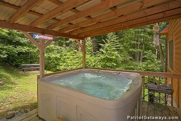 Hot tub on a covered deck at Bear Creek, a 4-bedroom cabin rental located in Pigeon Forge