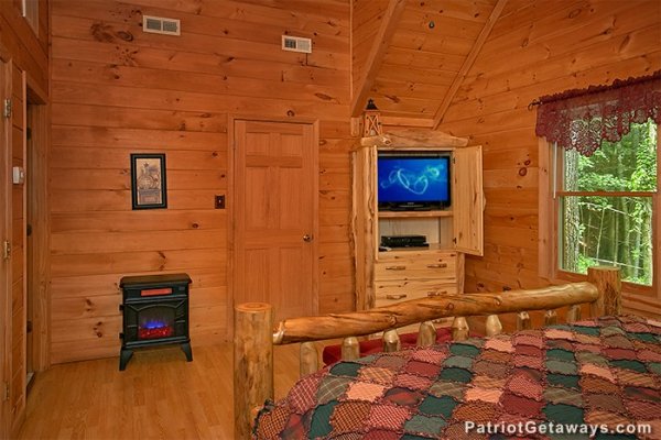 Bedroom with electric fireplace and tv armoire at Bear Creek, a 4-bedroom cabin rental located in Pigeon Forge
