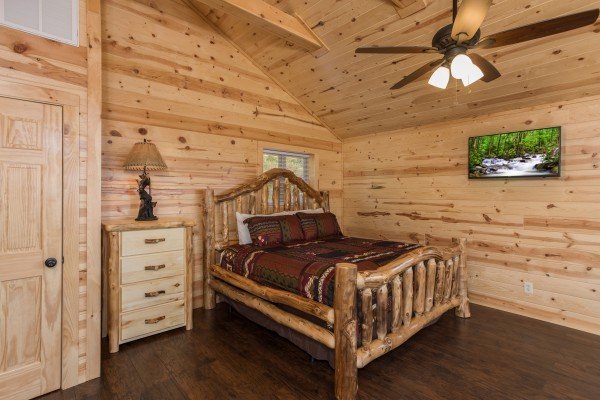 Bedroom with a log bed, dresser, lamp, and TV at The Sugar Shack, a 2 bedroom cabin rental located in Pigeon Forge