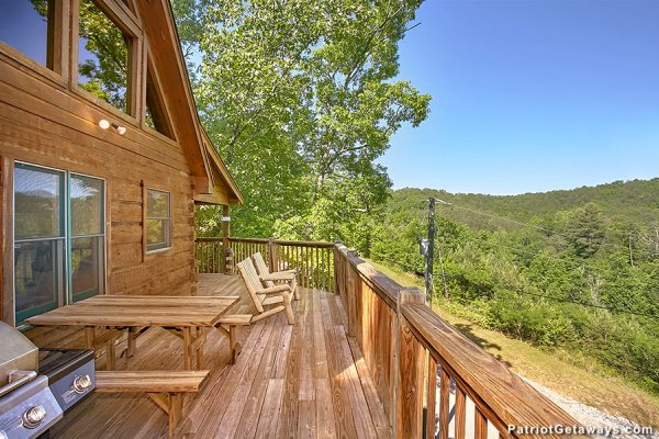 Deck with grill, picnic table, and Adirondack chairs at Picture Perfect Hideaway, a 2 bedroom cabin rental located in Pigeon Forge