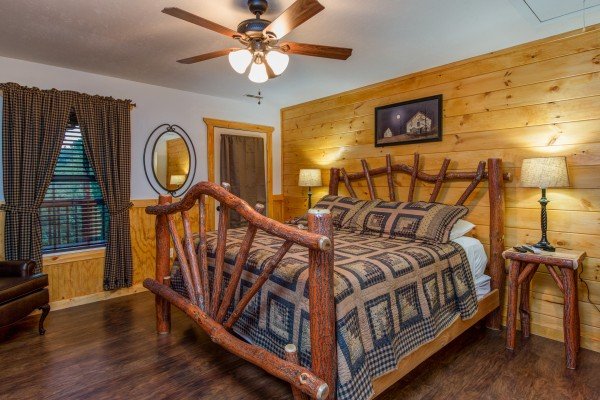 Log bed, night stands, and lamps in a bedroom at cabin 1 at The Settlement, a 10 bedroom cabin rental located in Pigeon Forge
