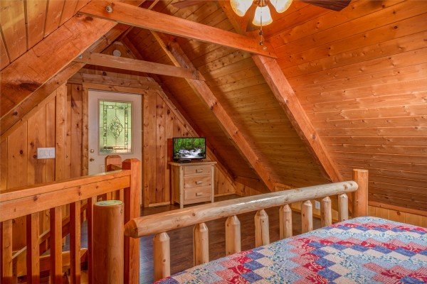 Dresser, TV, and deck access in a bedroom at The Settlement, a 10 bedroom cabin rental located in Pigeon Forge