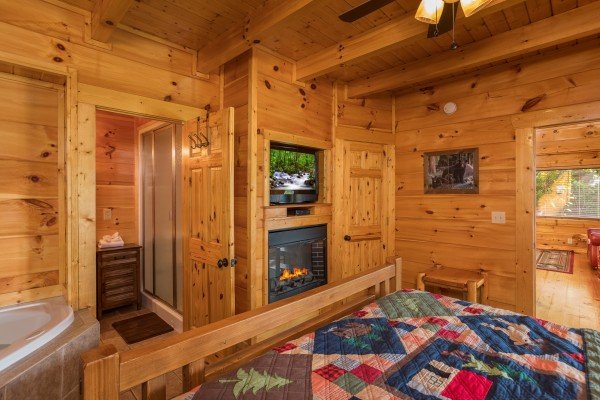Fireplace, TV, and jacuzzi in a bedroom at Graceland, a 4-bedroom cabin rental located in Pigeon Forge