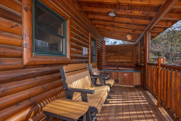 Hot tub and benches on the covered deck at Loving Every Minute, a 5 bedroom cabin rental located in Pigeon Forge