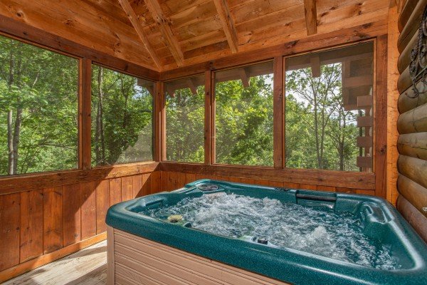 Hot tub on a screened in porch at Mountain Breeze, a 1 bedroom cabin rental located in Pigeon Forge