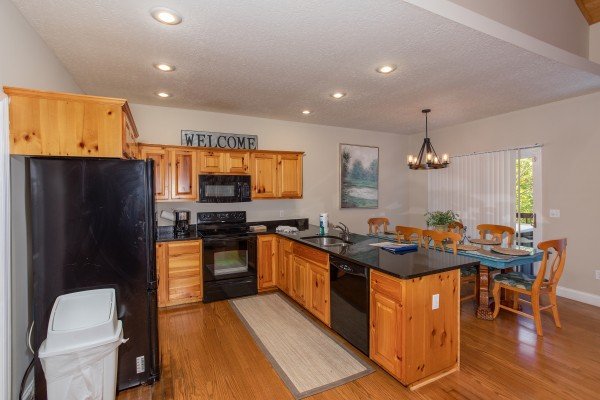 Kitchen with black appliances and dining space at Into the Woods, a 3 bedroom cabin rental located in Pigeon Forge
