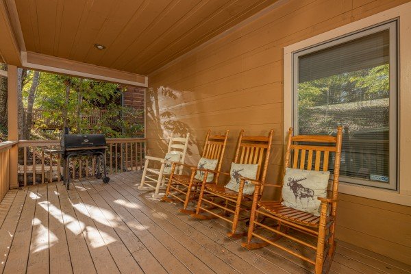 Rocking chairs and grill on a covered deck at Into the Woods, a 3 bedroom cabin rental located in Pigeon Forge