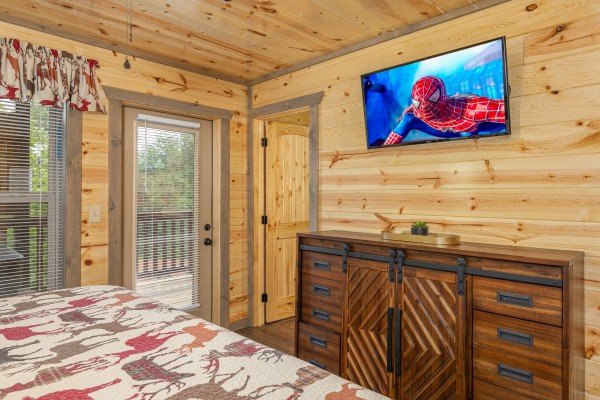Console table and TV in a bedroom with deck access and en suite bath at Alpine Adventure, a 4 bedroom cabin rental located in Pigeon Forge
