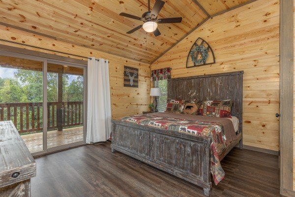 Bedroom with a king bed, night stand, lamp, and deck access at Alpine Adventure, a 4 bedroom cabin rental located in Pigeon Forge