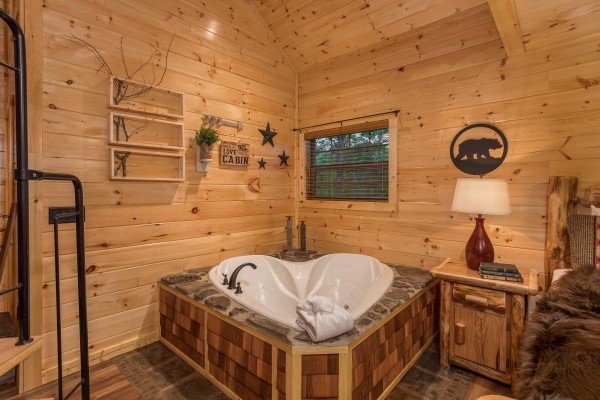 Heart shaped jacuzzi in the corner of the main floor at Pigeon Forge Treehouse, a 1 bedroom cabin rental located in Pigeon Forge
