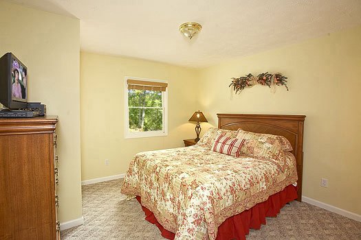 King sized bed with tv a chest of drawers at Heaven Sent, a 2-bedroom cabin rental located in Pigeon Forge