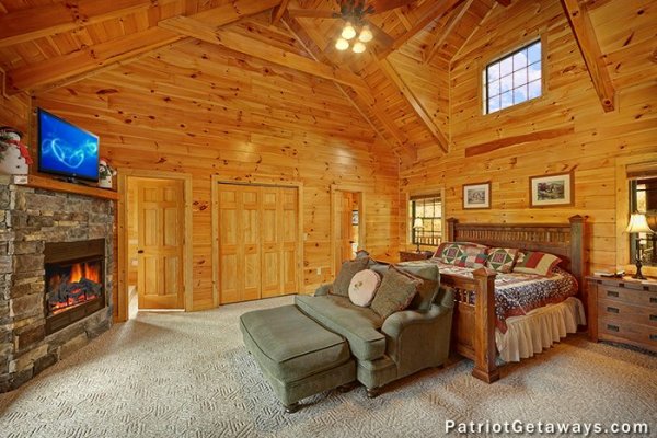 Main floor bedroom with king bed, loveseat, fireplace, and TV at Winter Wonderland, a 3 bedroom cabin rental located in Pigeon Forge