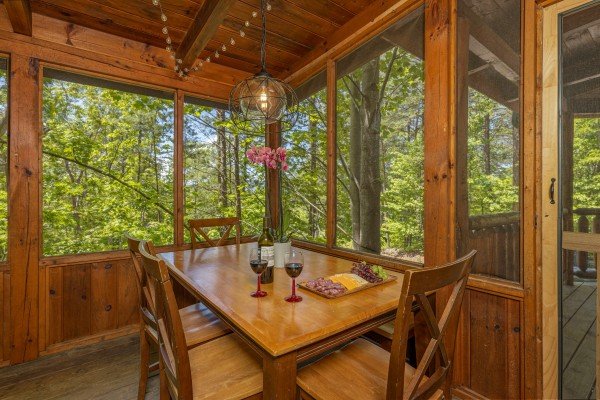 Dining table for four on a screened porch at Moonlit Pines, a 2 bedroom cabin rental located in Pigeon Forge