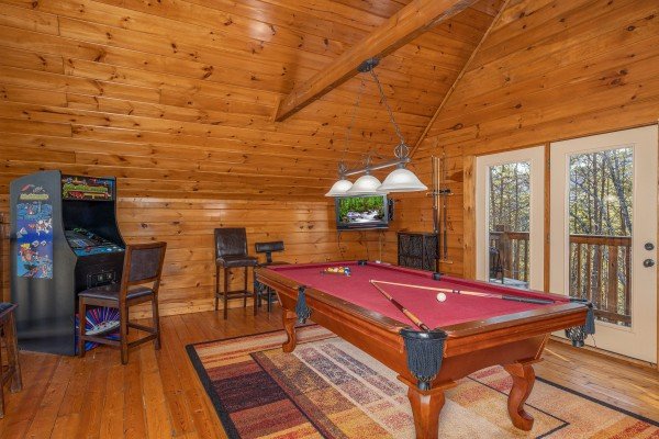 Pool table and arcade game in the loft at King of the Mountain, a 3 bedroom cabin rental located in Pigeon Forge