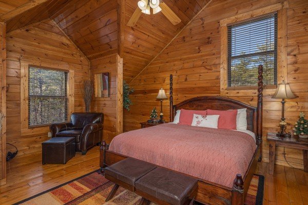 Bedroom with a king bed, chair, bench, and end tables at King of the Mountain, a 3 bedroom cabin rental located in Pigeon Forge