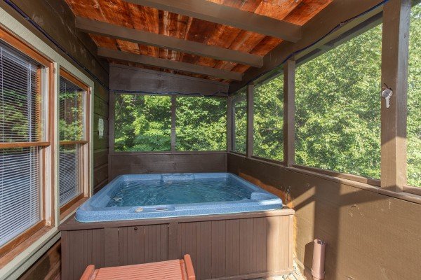 Hot tub on a screened porch at Wonders in the Sky, a 3 bedroom cabin rental located in Gatlinburg