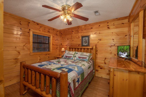 Bedroom with bed, dresser, and TV at Pine Splendor, a 5 bedroom cabin rental located in Pigeon Forge