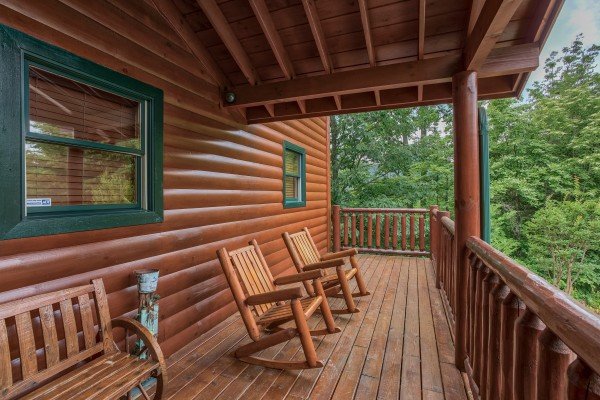Covered deck with bench and two log rockers at Horse'n Around, a 3 bedroom cabin rental located in Pigeon Forge