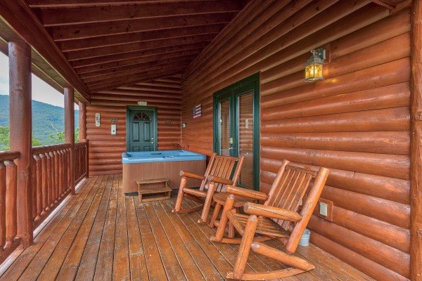 Rocking chairs and a hot tub facing the mountain views from the covered deck at Horse'n Around, a 3 bedroom cabin rental located in Pigeon Forge