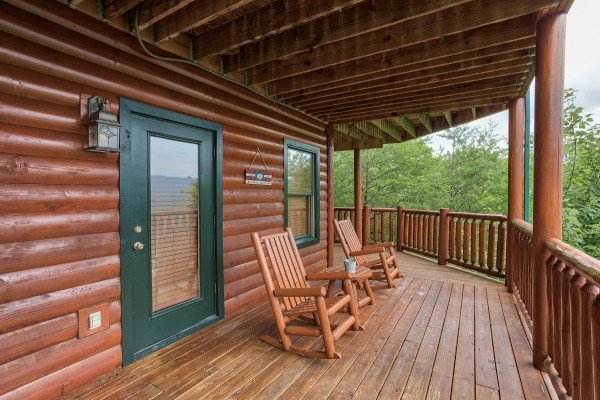 Two log rocking chairs on the covered deck at Horse'n Around, a 3 bedroom cabin rental located in Pigeon Forge