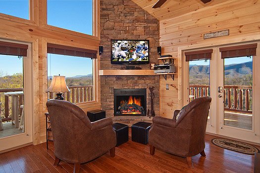 Two chairs with foot stools in front of stone fireplace at Horse'n Around, a 3 bedroom cabin rental located in Pigeon Forge