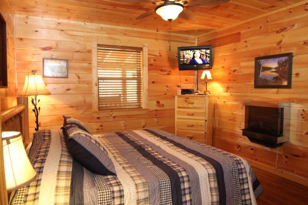 Bedroom with a TV, dresser, and fireplace at Rustic Romance, a 2 bedroom cabin rental located in Pigeon Forge