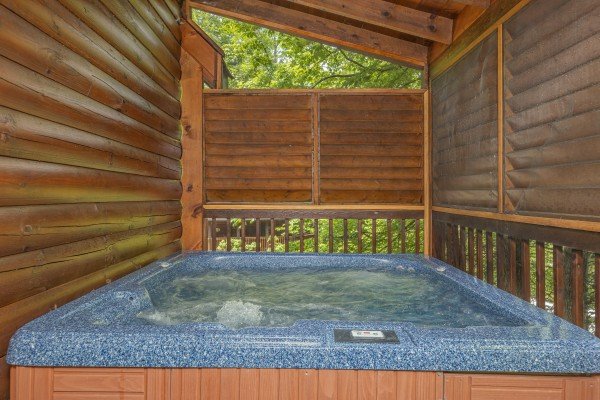 Hot tub on a screened porch at Location Location Location, a 1 bedroom cabin rental located in Pigeon Forge