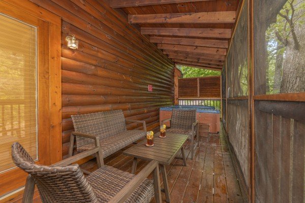 Furniture and hot tub on a screened in porch at Location Location Location, a 1 bedroom cabin rental located in Pigeon Forge