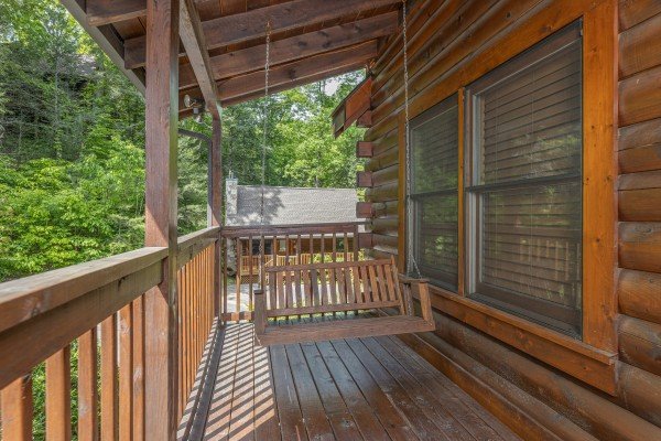 Swing on a covered porch at Location Location Location, a 1 bedroom cabin rental located in Pigeon Forge