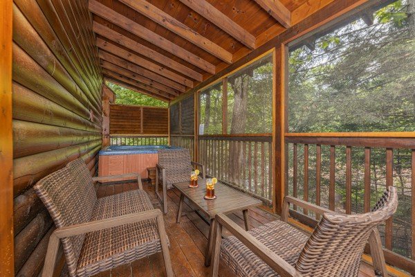Screened in porch with wicker seating and a hot tub at Location Location Location, a 1 bedroom cabin rental located in Pigeon Forge