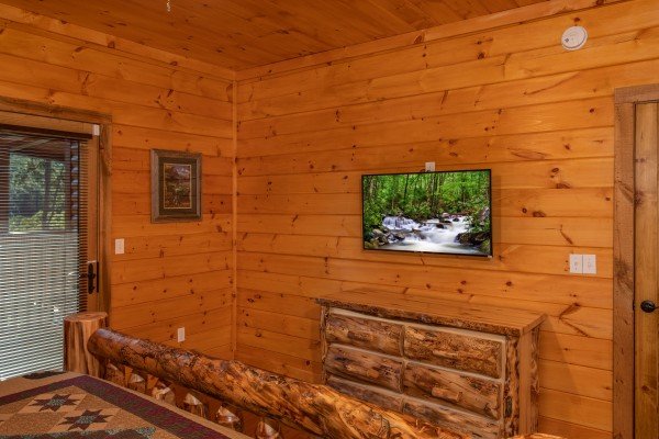 A bedroom with dresser, TV, and deck access at Four Seasons Palace, a 5-bedroom cabin rental located in Pigeon Forge