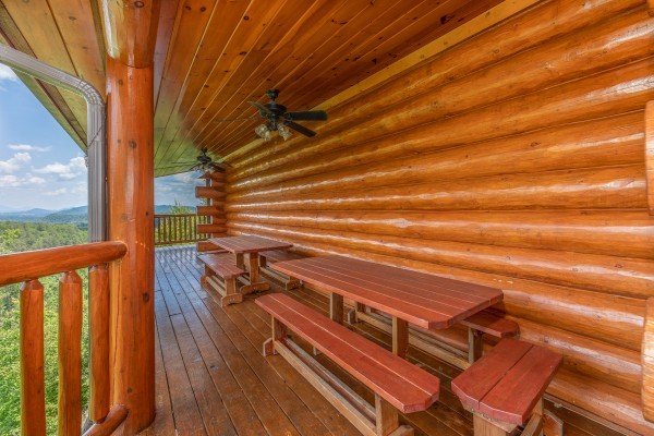 Picnic tables on a covered deck at God's Country, a 4 bedroom cabin rental located in Pigeon Forge