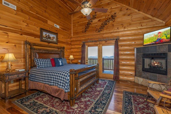 Bedroom with king bed, fireplace, tv, and deck access at God's Country, a 4 bedroom cabin rental located in Pigeon Forge