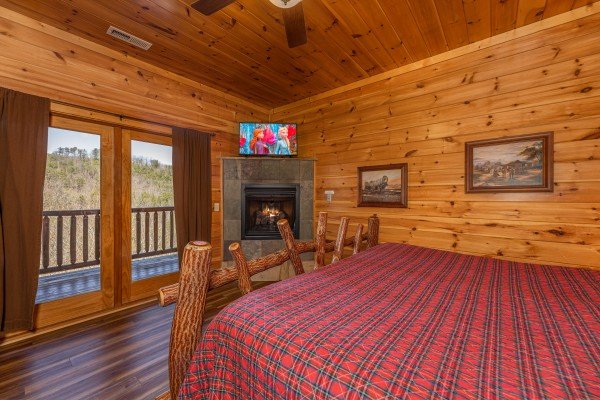 Fireplace, TV, and deck access in a bedroom at God's Country, a 4 bedroom cabin rental located in Pigeon Forge