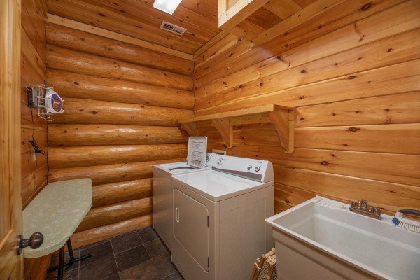 Laundry space with an iron and ironing board, washer and dryer, and utility sink at God's Country, a 4 bedroom cabin rental located in Pigeon Forge