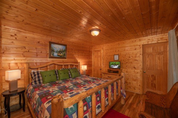 Bedroom with king log bed, two night stands and lamps, and a TV at Majestic Mountain, a 4 bedroom cabin rental located in Pigeon Forge