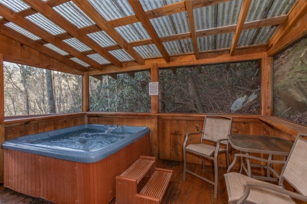 Hot tub on a screened, covered porch at Moonshiner's Ridge, a 1-bedroom cabin rental located in Pigeon Forge