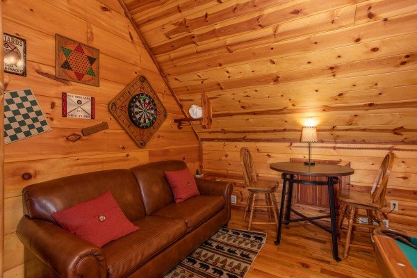 Sleeper sofa and table with chairs in the loft at Moonshiner's Ridge, a 1-bedroom cabin rental located in Pigeon Forge