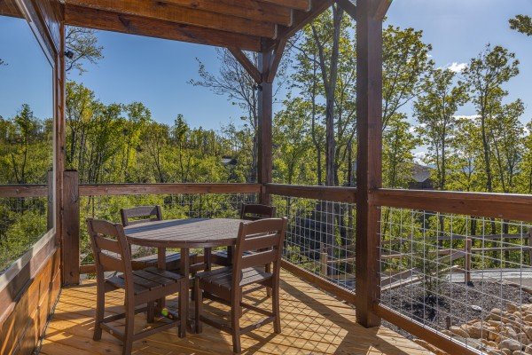 Covered deck with dining table for four at Heaven's Hill, a 3 bedroom cabin rental located in Gatlinburg