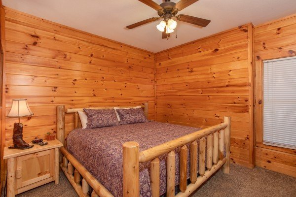 Bedroom with a king log bed, night stand, and lamp at The Cowboy Way, a 4 bedroom cabin rental located in Pigeon Forge