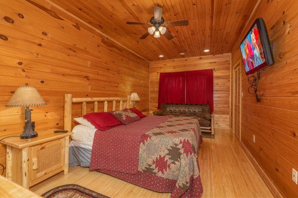Bedroom with a king bed, night stands, lamps, TV, and futon at Cabin Life, a 2 bedroom cabin rental located in Pigeon Forge