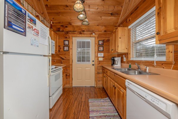 Galley kitchen with white appliances at Mickey's Playhouse, a 2 bedroom cabin rental located in Pigeon Forge