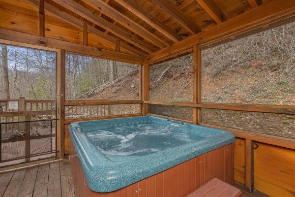 Hot tub on the screened in porch at Mickey's Playhouse, a 2 bedroom cabin rental located in Pigeon Forge