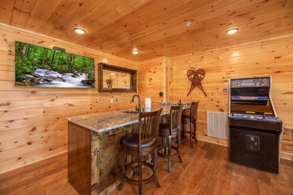 Wet bar, TV, and arcade game in the game room at Elk Horn Lodge, a 5 bedroom cabin rental located in Gatlinburg