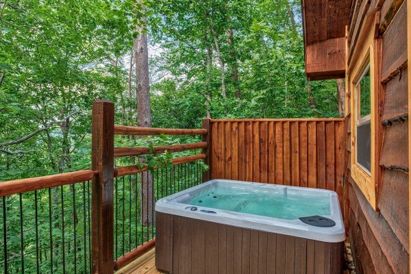 Hot tub on a deck with privacy fence at Smoky Mountain Treehouse, a 1 bedroom cabin rental located in Gatlinburg
