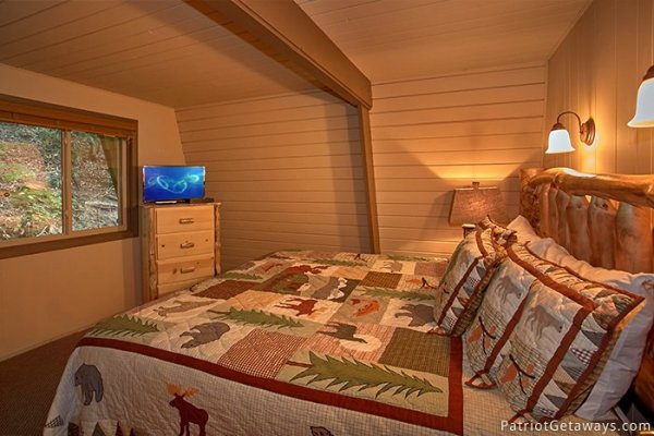 King sized be in main level bedroom at Gatlinburg Lodge, a 6-bedroom cabin rental located in Gatlinburg